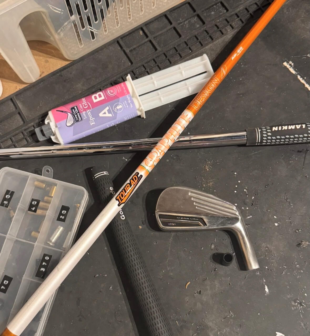 Golf club head, shafts and grips laid out on the workshop bench for a custom build.
