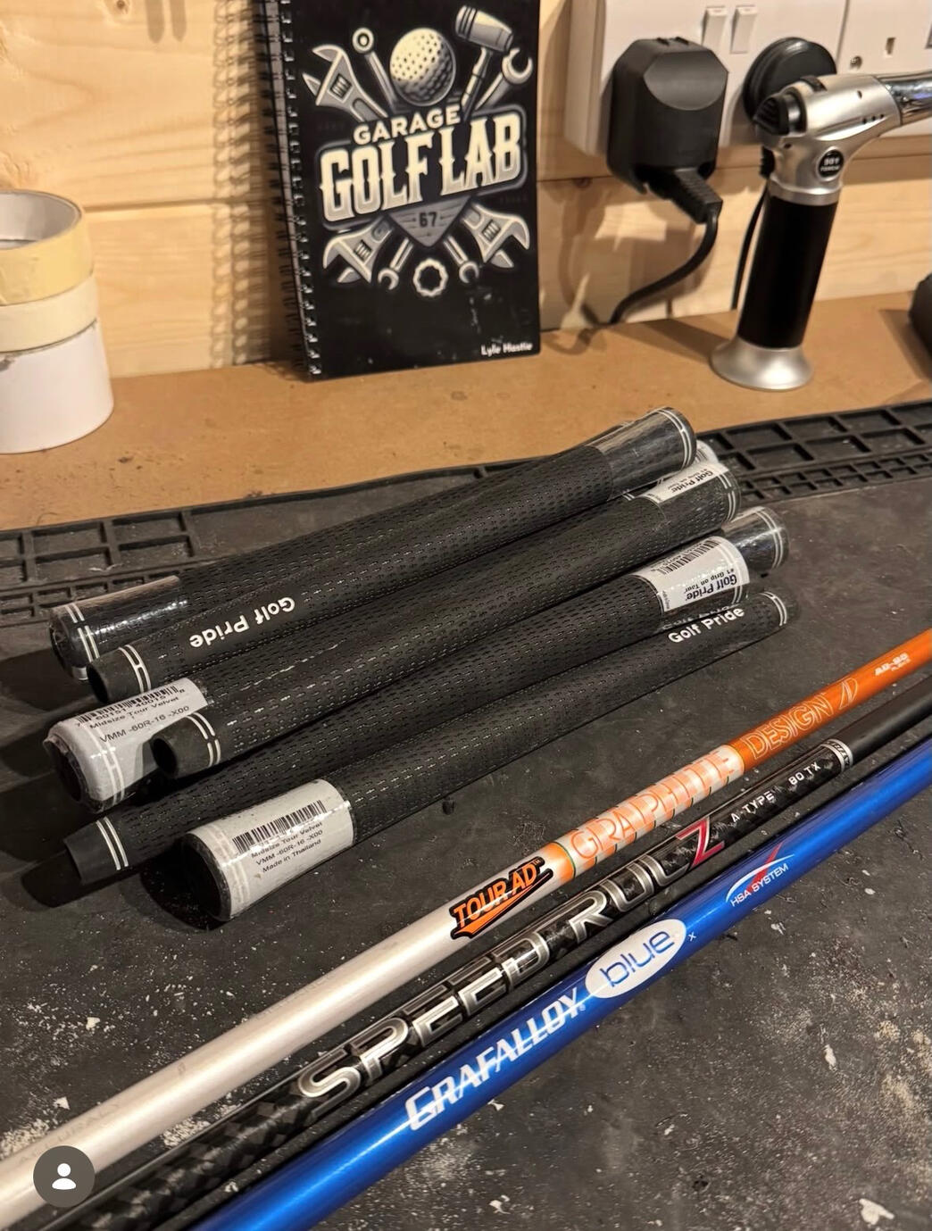 Golf grips and shafts laid out on The Garage Golf Lab workshop bench.